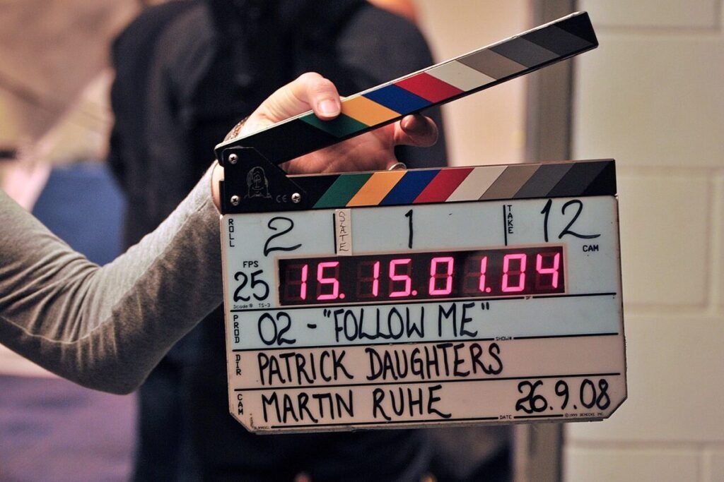 Clap de cinéma électronique tenu à la main sur un plateau de tournage, avec son affichage de timecode rouge