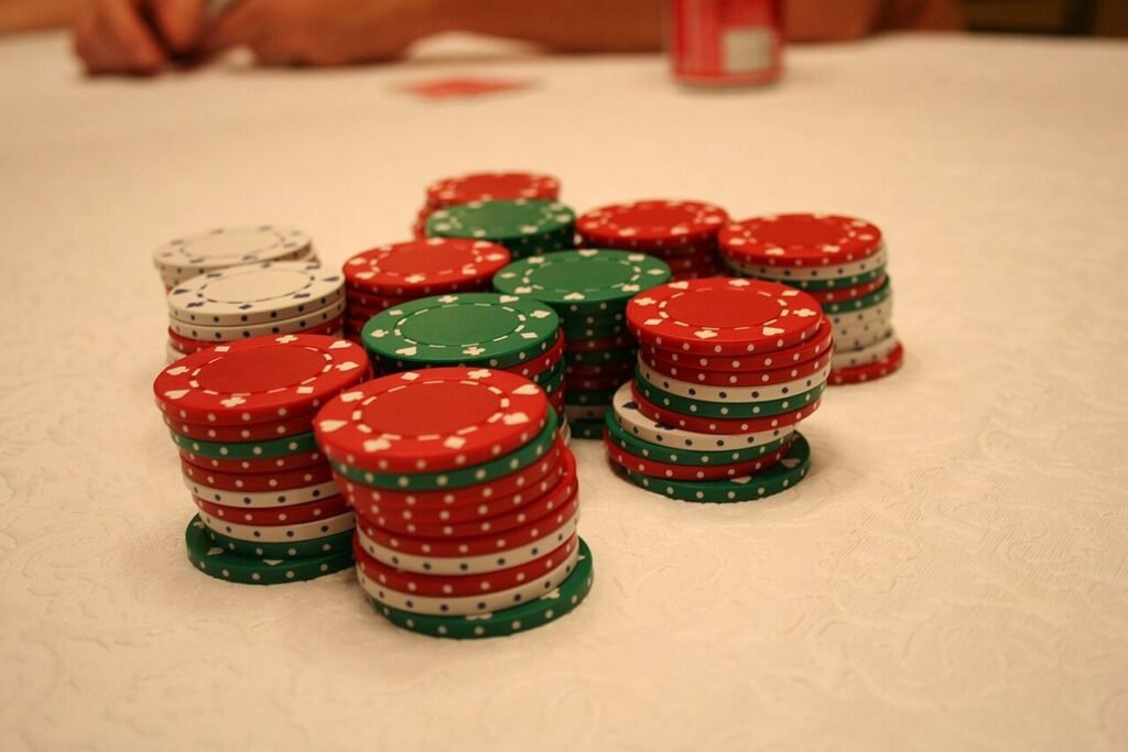 Piles de jetons de poker rouges, verts et blancs posées sur un tapis clair