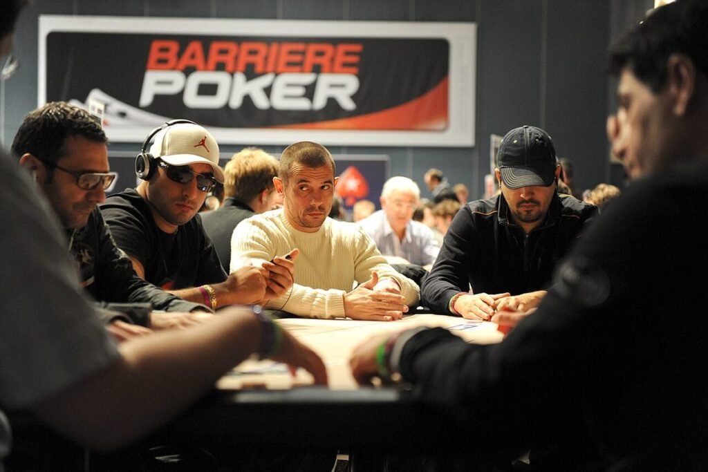 Joueurs concentrés autour d'une table de l'European Poker Tour de Deauville, devant une bannière Barrière Poker