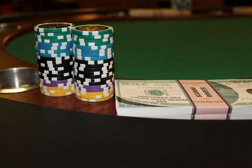 Deux piles de jetons de poker à côté de liasses de billets sur une table au tapis vert
