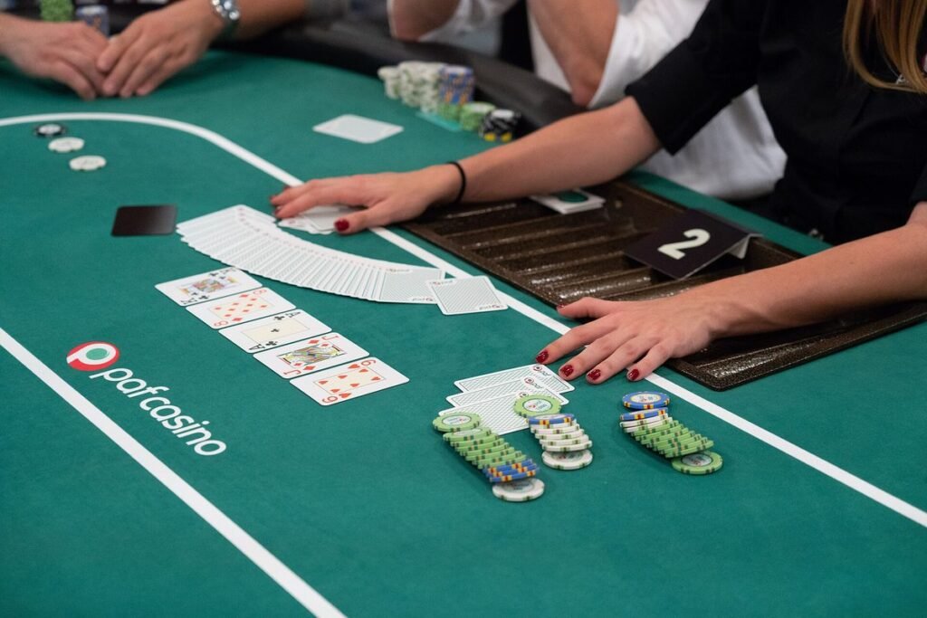 Croupier distribuant les cartes sur une table de poker au tapis vert entourée de joueurs et de leurs jetons
