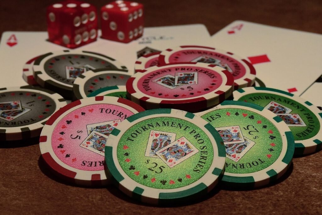 Jetons de poker colorés étalés avec des cartes et deux dés rouges sur une table en bois