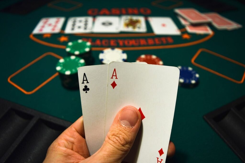 Main tenant une paire d'As au-dessus d'un tapis de casino vert avec des jetons et des cartes