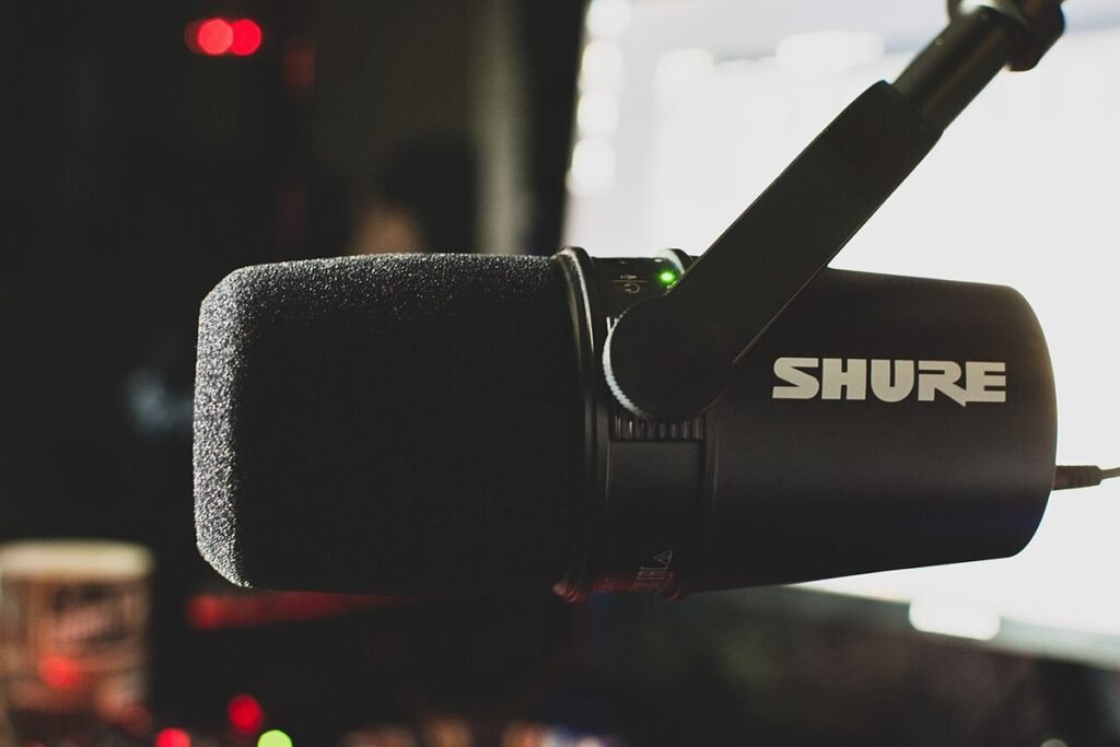 Micro de streaming Shure monté sur un bras articulé, devant un écran allumé dans une pièce sombre